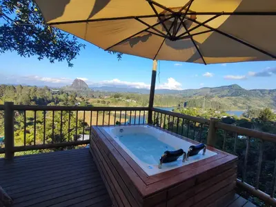 a hot tub on a deck with an umbrella at Breeze Glamping -Guatape in El Peñol