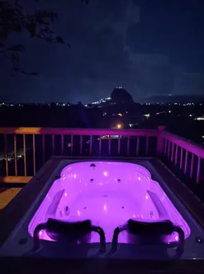 a purple hot tub on a balcony at night at Breeze Glamping -Guatape in El Peñol