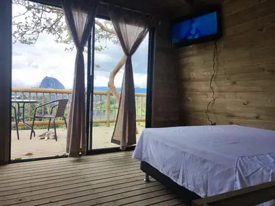 a bedroom with a bed and a balcony with a tv at Breeze Glamping -Guatape in El Peñol