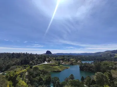an aerial view of a lake with a rainbow in the sky at Breeze Glamping -Guatape in El Peñol