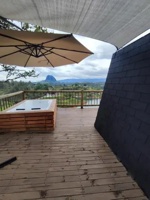 a patio with an umbrella and a bed on a deck at Breeze Glamping -Guatape in El Peñol