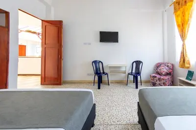 two beds in a room with two chairs and a table at Hotel Ayenda Macondo in Manizales