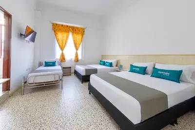 a hotel room with two beds and a chair at Hotel Ayenda Macondo in Manizales