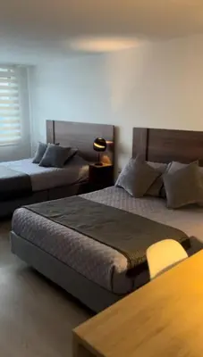 a bedroom with two beds and a table with a lamp at Apartahotel La Arboleda HC in Manizales