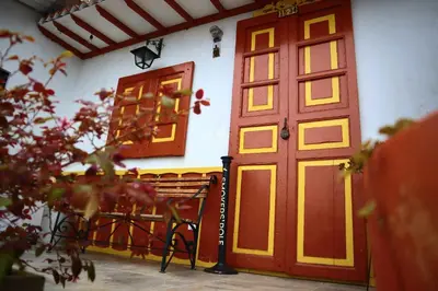 a red door and a bench in front of a building at Apartahotel La Arboleda HC in Manizales
