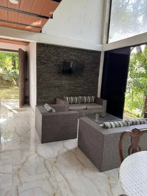 a patio with wicker furniture and a tv on a brick wall at EL MILAGRO FINCA VACACIONAL in San Rafael