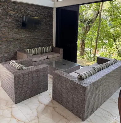 a patio with two couches and a tv on a brick wall at EL MILAGRO FINCA VACACIONAL in San Rafael