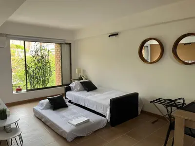 a bedroom with two beds and a mirror on the wall at Poblado Park Aparta Estudio in El Poblado