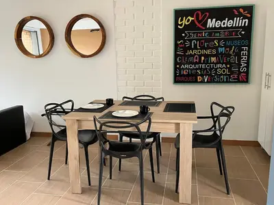 a dining room table with black chairs and a mirror at Poblado Park Aparta Estudio in El Poblado