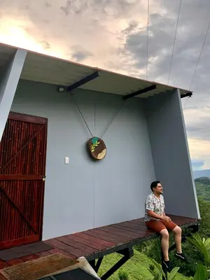 a man sitting on a bench in front of a house at La Paloma Glamping in Palestina