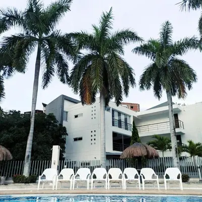 a building with palm trees and chairs in front of a pool at Apartamento vista piscina principal in Santa Fe de Antioquia