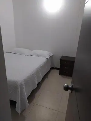a small bedroom with a bed and a night stand at Apartamento vista piscina principal in Santa Fe de Antioquia