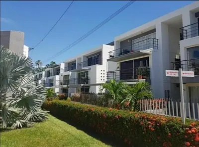 a row of white apartment buildings with bushes and trees at Apartamento vista piscina principal in Santa Fe de Antioquia