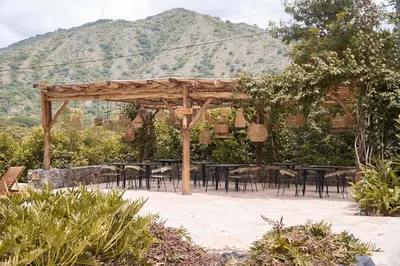 a group of tables and chairs under a wooden pergola at Nativa Refugio Escondido in Santa Fe de Antioquia