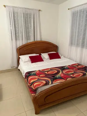 a bed with a wooden frame and red pillows on it at VILLA ALEJANDRIA - CABAÑA LAMARIQUITA-CABAÑA ORQUIDEA-CABAÑA CARAMBOLa in Mariquita