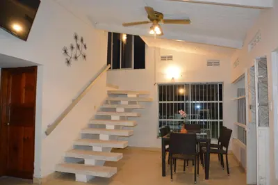 a staircase in a living room with a table and chairs at VILLA ALEJANDRIA - CABAÑA LAMARIQUITA-CABAÑA ORQUIDEA-CABAÑA CARAMBOLa in Mariquita