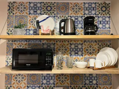 a microwave on a shelf with plates and cups at Hospedaje en Medellí cerca a Laureles NID103 By Roots Rentals in Medellín