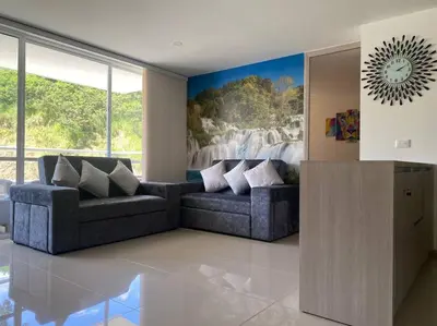 a living room with two couches and a painting of a waterfall at Lugar encantador en Santa Fe de Antioquia in Santa Fe de Antioquia