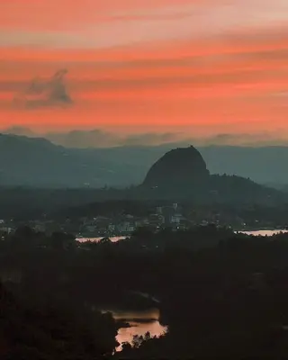 a sunset with a view of a city and a mountain at Noches de Guatapulco in Guatapé