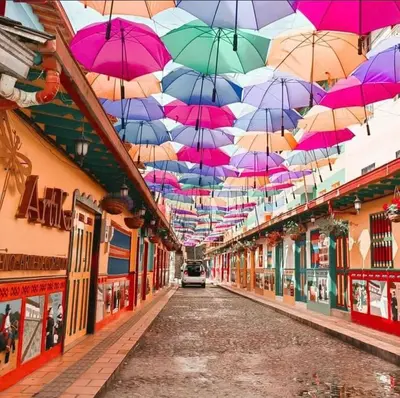 a row of umbrellas hanging from an alley way at Noches de Guatapulco in Guatapé