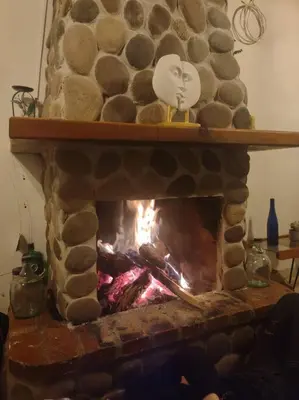 a stone fireplace with a fire in it at Casa Rustica con chimenea en su interior, rodeado de los cuatro elementos tierra, fuego, aire y agua, ubicada en sector tranquilo, para descansar en familia o amigos, in Mazo