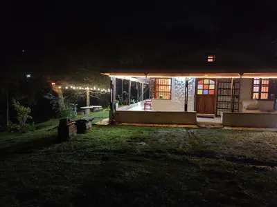 a small house lit up at night with lights at Casa Rustica con chimenea en su interior, rodeado de los cuatro elementos tierra, fuego, aire y agua, ubicada en sector tranquilo, para descansar en familia o amigos, in Mazo