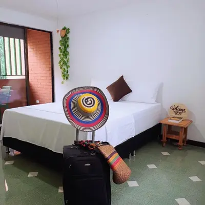 a room with a bed and a hat on a suitcase at Moradia Laureles Medellin in Medellín
