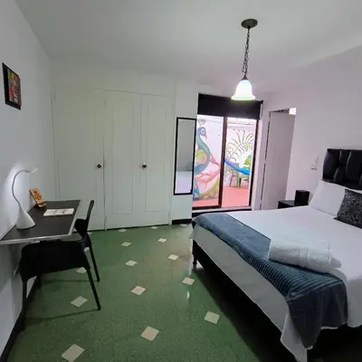 a bedroom with a bed and a table and a desk at Moradia Laureles Medellin in Medellín