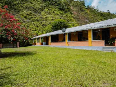 a yellow house with a grass yard in front of it at Finca Hotel Rios Claros in San Luis