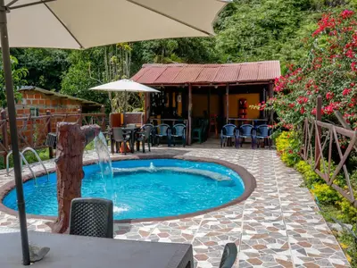 a pool with an umbrella and a fountain at Finca Hotel Rios Claros in San Luis