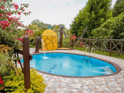 a pool with a water fountain in a garden at Finca Hotel Rios Claros in San Luis