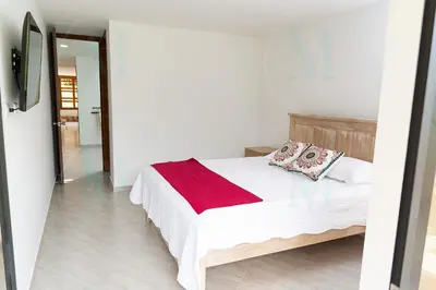 a white bedroom with a bed with a red blanket at La Casa de Ana 2 in Jardin