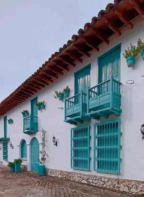 a white building with green doors and windows at El Santorini colombiano in Puerto Triunfo