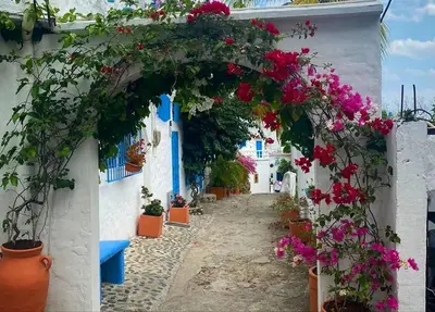 an alley with flowers on a white building at El Santorini colombiano in Puerto Triunfo