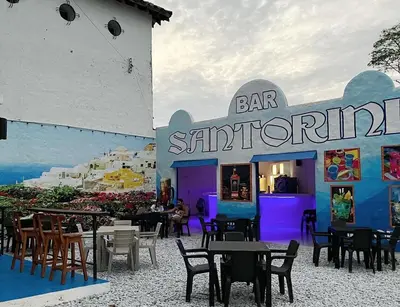 a bar with tables and chairs in front of a restaurant at El Santorini colombiano in Puerto Triunfo