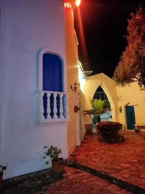 a white building with a blue window and a balcony at El Santorini colombiano in Puerto Triunfo