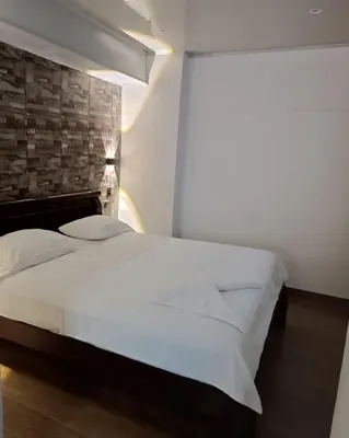 a bedroom with a white bed and a brick wall at El Santorini colombiano in Puerto Triunfo