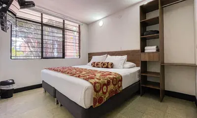 a bedroom with a bed and a book shelf at Hotel Boutique Estadio in Medellín