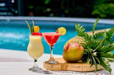 two drinks on a cutting board with fruit on a table at Hotel Capri Doradal in Doradal