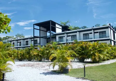 a house with palm trees in front of it at Hotel Capri Doradal in Doradal