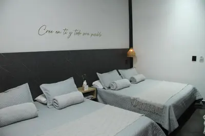 two beds in a room with a sign on the wall at Hotel Capri Doradal in Doradal