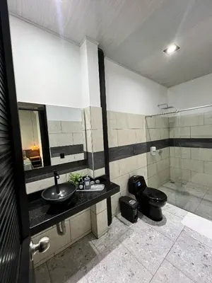 a bathroom with a black toilet and a sink at Hotel Capri Doradal in Doradal