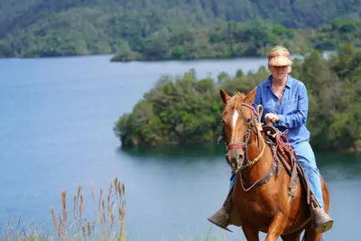 a woman riding a horse in front of a lake at Bethel Lozana Guatape in Guatapé