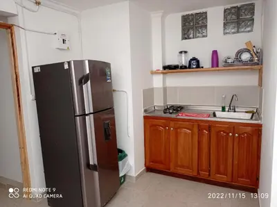 a kitchen with a stainless steel refrigerator and wooden cabinets at Estadio APARTE HOTEL 203 in Medellín