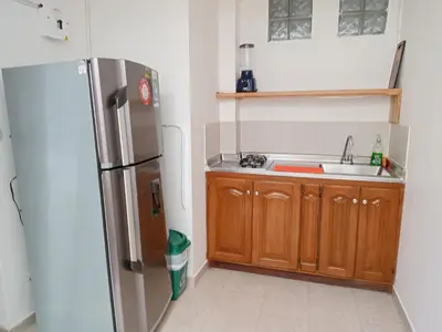 a kitchen with a stainless steel refrigerator and wooden cabinets at Estadio APARTE HOTEL 203 in Medellín