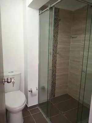 a bathroom with a toilet and a glass shower at Estadio APARTE HOTEL 203 in Medellín