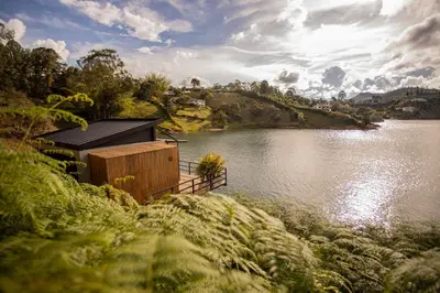 a building on a hill next to a body of water at La Pausa Hotelbistro in Guatapé