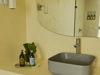 a bathroom sink with two bottles and a mirror at La Pausa Hotelbistro in Guatapé