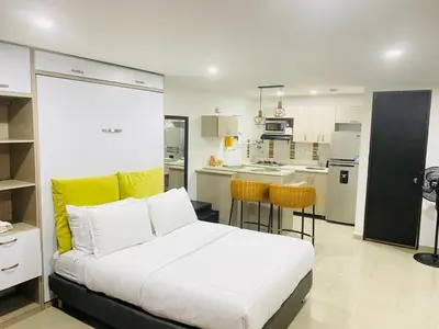 a bedroom with a white bed and a kitchen at 1009 Apartamento zona exclusiva Poblado in Medellín