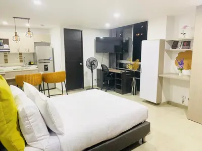 a bedroom with a white bed and a kitchen at 1009 Apartamento zona exclusiva Poblado in Medellín